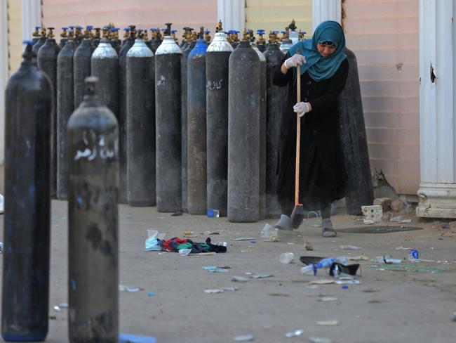 A woman cleans debris next to oxygen bottles outdoors at the Ibn Al-Khatib Hospital in Baghdad, after a fire erupted in the medical facility reserved for the most severe coronavirus cases. Picture: AFP