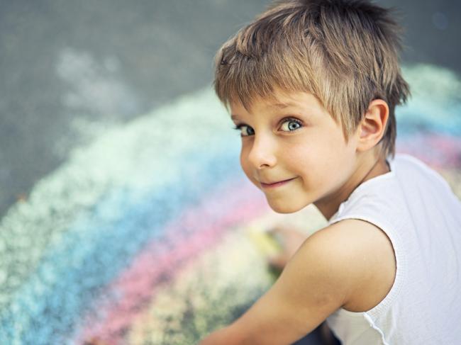 Smiling little boy chalking on the concrete  street