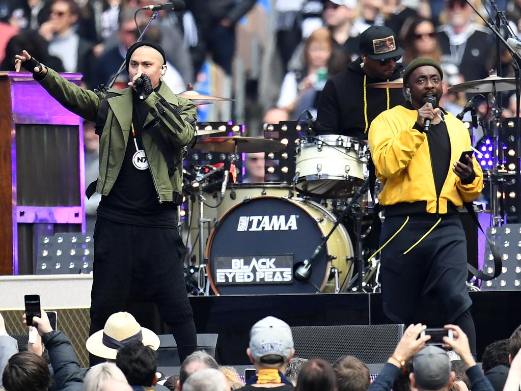 Singer will.i.am (right) holds his phone as he performs before the 2018 AFL Grand Final. (AAP Image/Julian Smith)