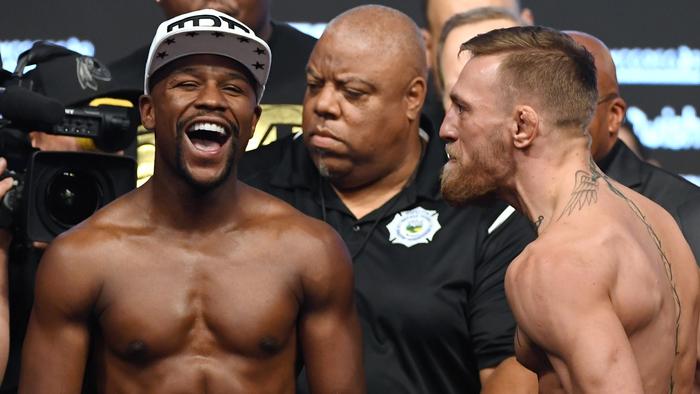 LAS VEGAS, NV - AUGUST 25: Boxer Floyd Mayweather Jr. (L) laughs after facing off with UFC lightweight champion Conor McGregor during their official weigh-in at T-Mobile Arena on August 25, 2017 in Las Vegas, Nevada. The two will meet in a super welterweight boxing match at T-Mobile Arena on August 26. (Photo by Ethan Miller/Getty Images)