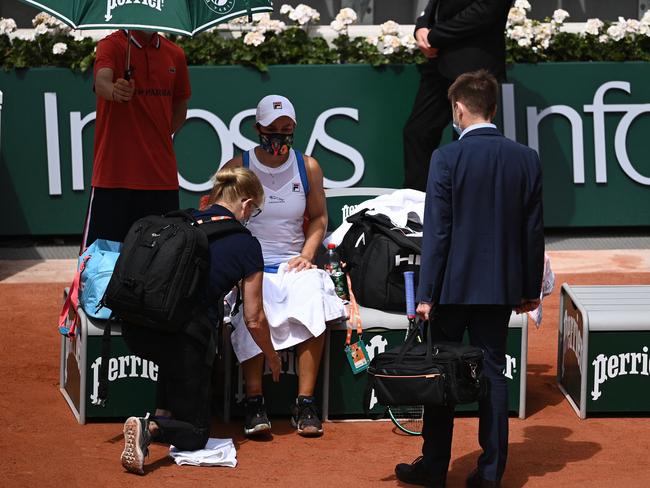 Australia's Ashleigh Barty is treated by medical staff during her women's singles second round tennis match against Poland's Magda Linette on Day 5 of The Roland Garros 2021 French Open tennis tournament in Paris on June 3, 2021. (Photo by Anne-Christine POUJOULAT / AFP)