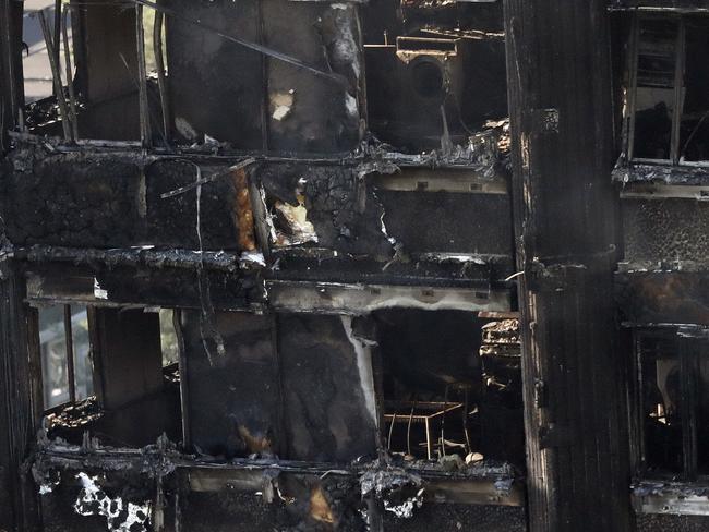 Remains of furniture are seen through the windows as smoke still emerges from the charred Grenfell Tower in London. Picture: AP Photo/Frank Augstein