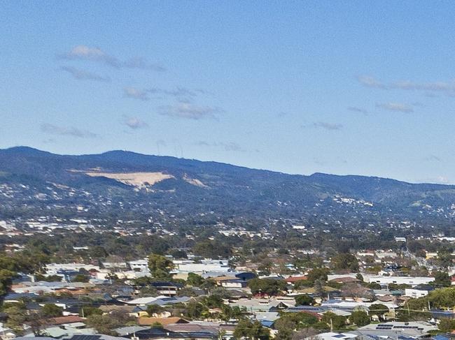 Aerial view looking down on new, modern Adelaide housing development with mixed house & architectural styles: single level houses, townhouses, construction site, green space, established suburb & city in background. Picture: iStock/BeyondImages