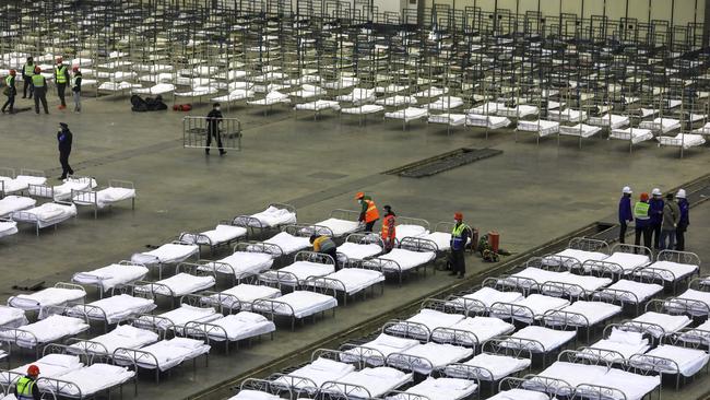 Workers arrange beds in a convention centre that has been converted into a temporary hospital in Wuhan. Picture: AP