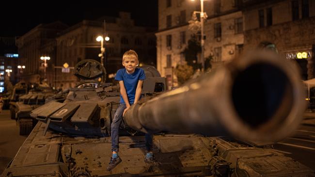 A boy poses on top of a burnt-out Russian tank in Kyiv. Picture: Getty Images