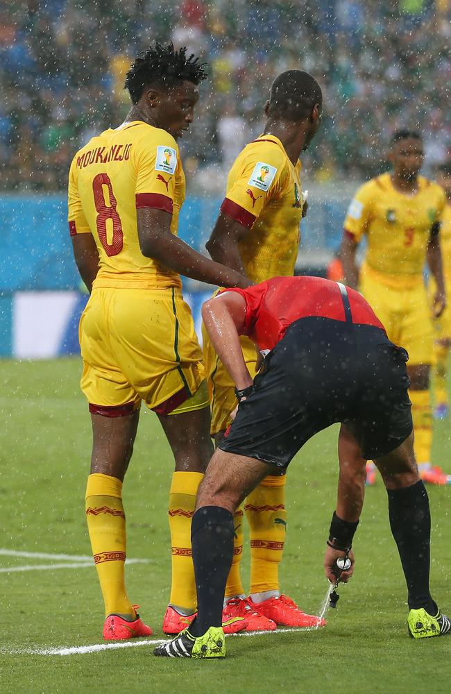 Referee Wilmar Roldan sprays the temporary line for a free kick as Benjamin Moukandjo and Enoh Eyong of Cameroon form a wall.