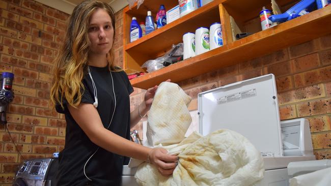 Clermont Country Motor Inn housekeeper Jess Walsh shows what the discoloured water in Clermont had done to the motel's laundry. Photo: Zizi Averill
