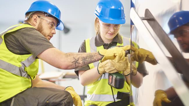 An apprentice installs handrails in an office refurbishment.