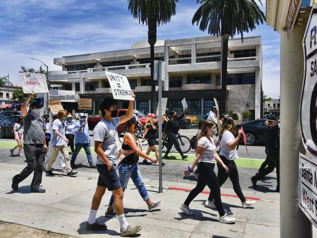 Protesters walk along Ocean Boulevard and chant slogans while blocking an intersection in Santa Monica.