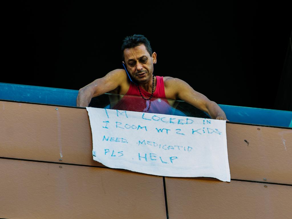 A man hangs a sign outside his hotel window at Peppers Hotel, Adelaide. Picture: Morgan Sette/The Australian