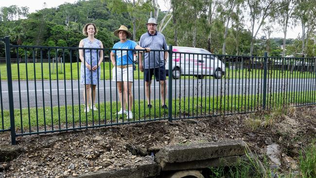 A narrow strip of grass is all the safe walking space school students have while they work their way around a fenced drain on McManus St, trying to get to school as traffic passes just metres away. Picture: Brendan Radke