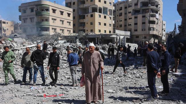 An elderly Palestinian man walks past people gathered near the rubble of the Elias Tarazi family house, after it was destroyed in an Israeli strike in al-Sabra neighbourhood in Gaza City on March 19. Picture: AFP