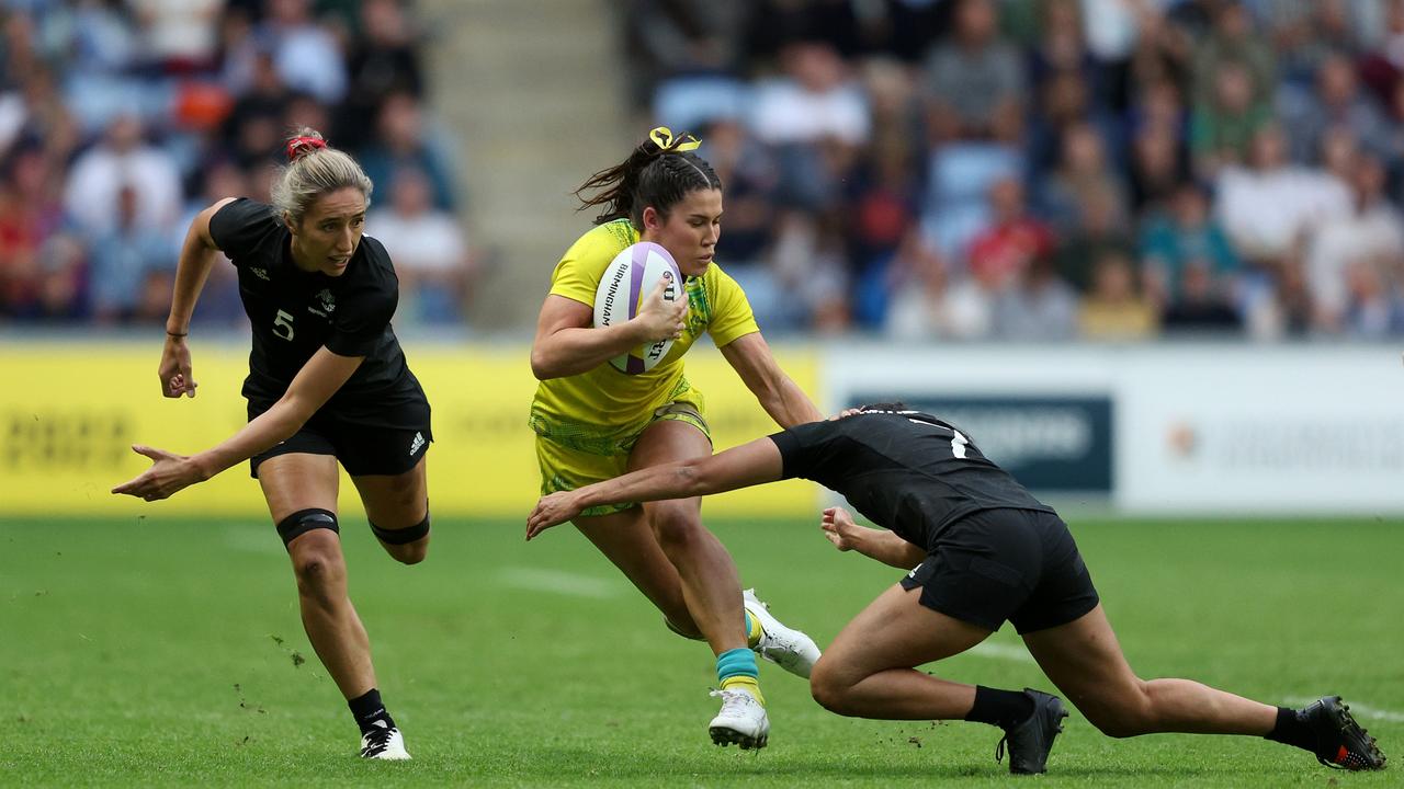 Charlotte Caslick of Team Australia is tackled by Tyla Nathan-Wong and Sarah Hirini of Team New Zealand during the Women's Rugby Sevens Semi-Final match between Team Australia and Team New Zealand.