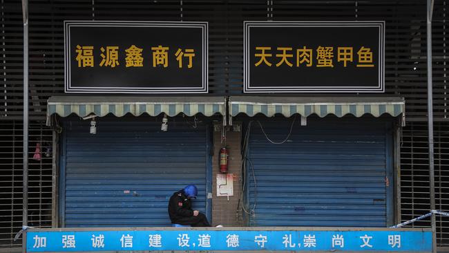 A security guard sits outside the closed Huanan Seafood Wholesale Market, believed to be the source of the new coronavirus. Picture: Getty Images