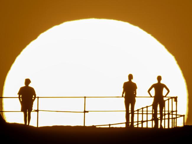 People watch as the sun rises over Ben Buckler Point in Bondi yesterday as Sydney sweltered in boiling hot weather. Picture: Brook Mitchell/Getty Images