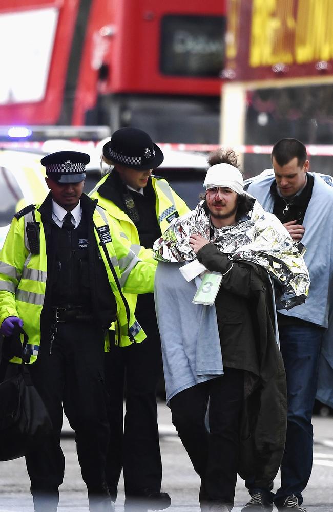 A member of the public bleeding from the head is helped by emergency services near Westminster Bridge and the Houses of Parliament.