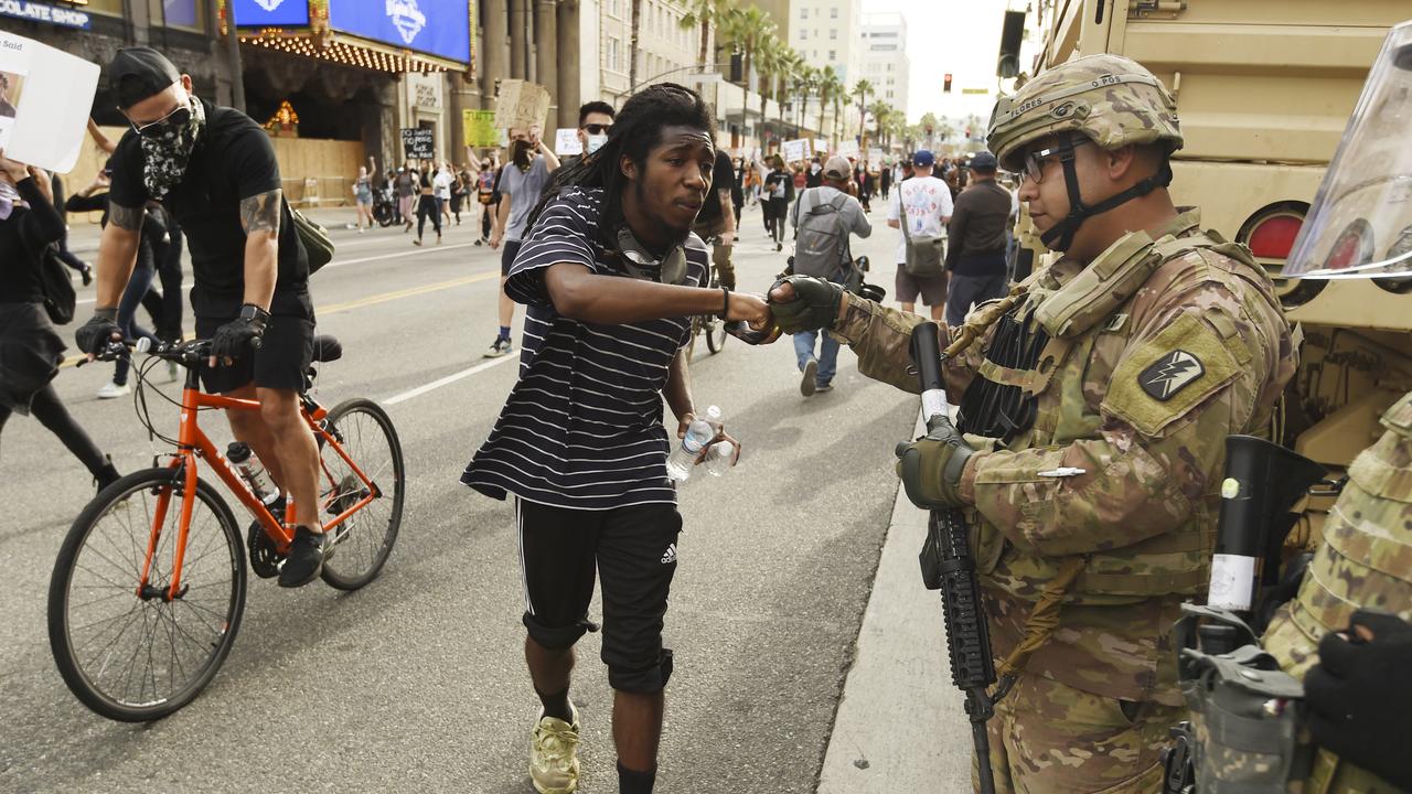 A protest rally participant bumps fists with a National Guardsman on Hollywood Boulevard in Los Angeles. Picture: AP/Chris Pizzello