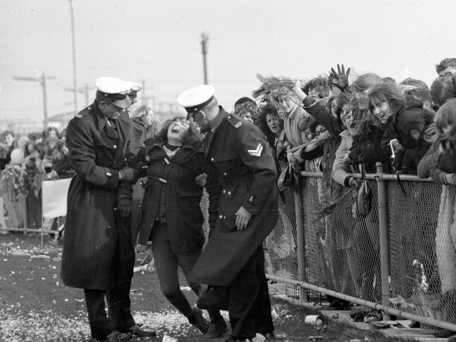 June 14, 1964: Police help one distressed fan waiting at the airport. Picture: Herald Sun Image library