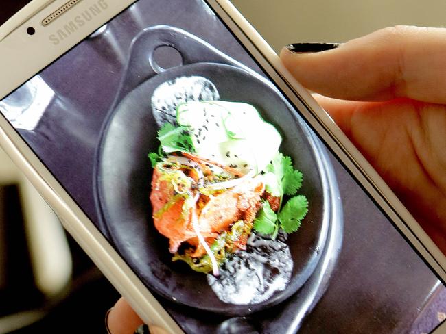 Food blogger Laura Kelly, who runs blog Eatin' Mess, shooting a phone pic of the soft shell crab dish at Fiction Bar and Restaurant, Raby Bay - Brisbane's top chefs have pleaded with diners to keep food selfies to a minimum - and to snap them quickly. Pic Mark Cranitch.