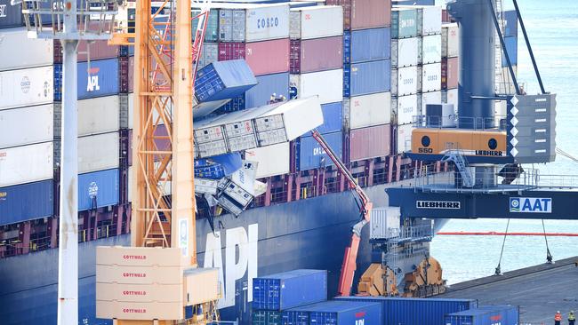 Workers from logistics company QUBE inspect toppled containers on board the Singapore-flagged container ship APL England at the Port of Brisbane. (AAP Image/Dan Peled)