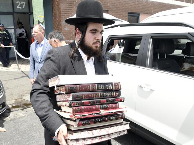 Church members remove religious material from Adass Israel synagogue after an overnight fire attack. Picture: Andrew Henshaw