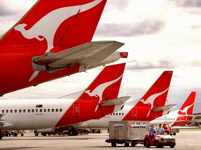 Qantas aircraft tails at Kingsford Smith Airport in Sydney as baggage handlers deliver luggage. plane airline logo tail/Qantas/Airways/Ltd