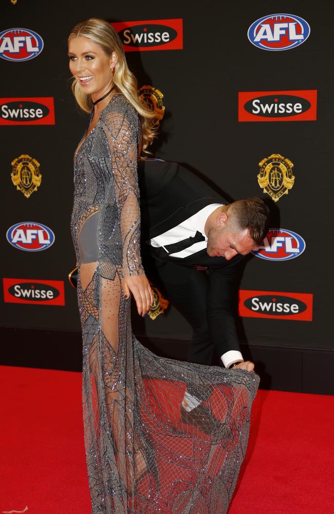 Travis Cloke turns stylist for the night as he adjusts the dress of partner Rebeccah Panozza as they attend the 2015 Brownlow medal. Pic: Michael Klein.