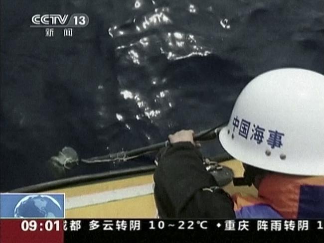 In this image taken from video, a member of a Chinese search team uses an instrument to detect electronic pulses while searching for the missing Malaysia Airlines Flight 370.