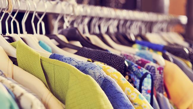 some used clothes hanging on a rack in a flea market