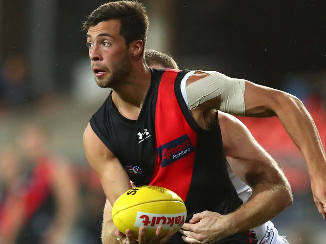 GOLD COAST, AUSTRALIA - AUGUST 07: Kyle Langford of the Bombers handballs whilst being tackled during the round 10 AFL match between the Essendon Bombers and the Greater Western Sydney Giants at Metricon Stadium on August 07, 2020 in Gold Coast, Australia. (Photo by Chris Hyde/Getty Images)