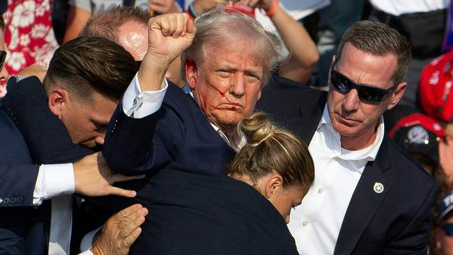 Donald Trump, with blood on his face, is surrounded by Secret service agents as he is taken off the stage at a campaign event in Butler, Pennsylvania, following an assassination attempt. Picture: Rebecca Droke/AFP