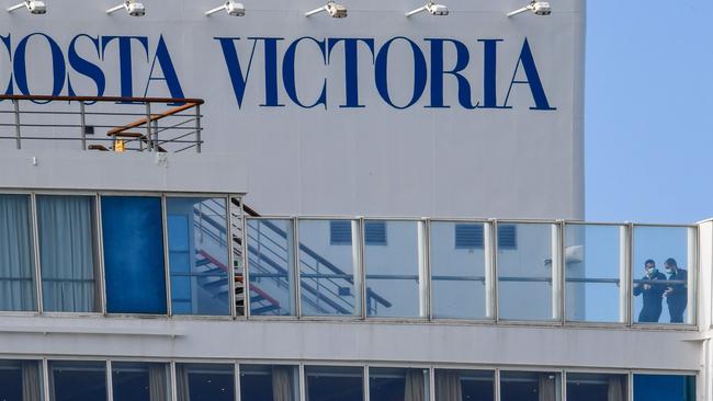 Men wearing a face mask walk across a top deck aboard the Costa Victoria. Picture: Andreas Solaro/AFP