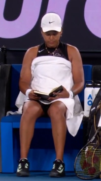 Naomi Osaka relaxes with a book between sets