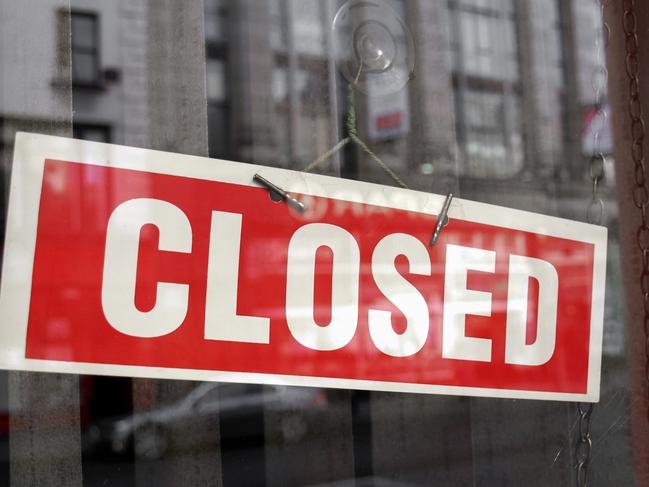 Closed sign in a shop showroom with reflections - red sign over desaturated background