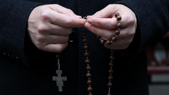 A George Pell supporter with some rosary beads outside the Supreme Court. Picture: AAP