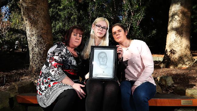 Sisters Jo Fisher, 38, of Glenorchy, left, Rose Mazurek, 22, of West Moonah, and Bek Morris, 33, of Howrah, and their family are still seeking answers to the disappearance of their brother, Jason Mazurek, in 2002. The sisters are siting on a bench dedicated to him at the Royal Tasmanian Botanical Gardens. Picture: NIKKI DAVIS-JONES