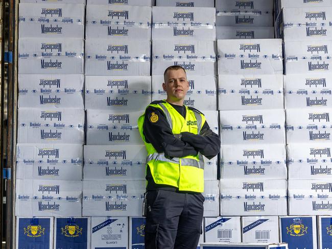 Border Force HQ finds illegal tobacco in shipping containers. Australian Border Force officer Jake stands in front of a shipping container full of illegally imported cigarettes. Picture: Jake Nowakowski