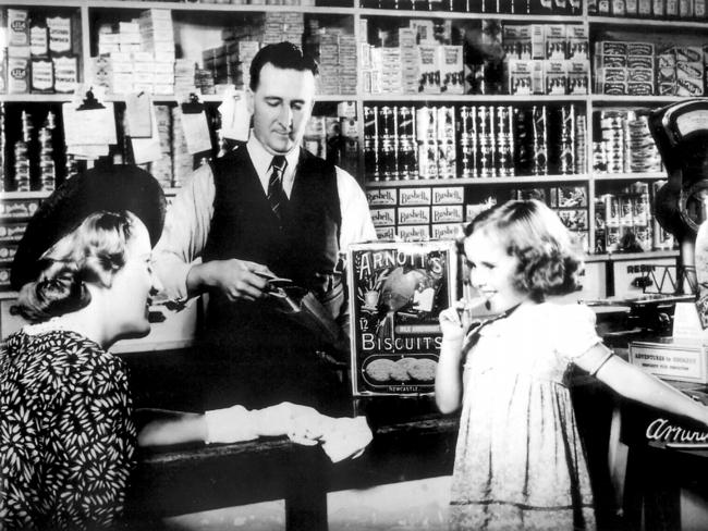 Young child tries Arnott's milk arrowroot biscuit in grocery shop in 1940s. Pic Handout      Historical        New South Wales (NSW) / Shopping / Shops