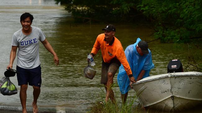 Wet weather in Townsville. Poultry farmer Jeff Ironside brings employees Dennis Bernas and AJ Willis back across the Bohle River, cut by flood water at Allambie Lane. Picture: Evan Morgan