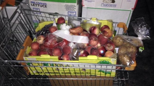 A trolley full of fruit and vegetables dumped behind a shopping centre.