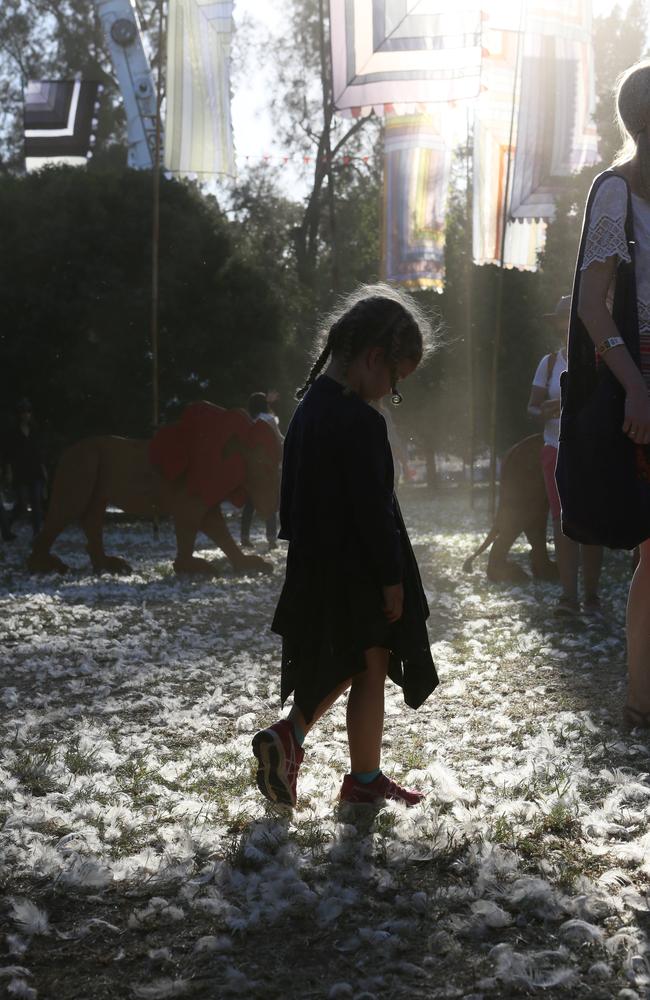 A little girl walks through the feathers on the ground at Womad. Picture: AAP / Emma Brasier