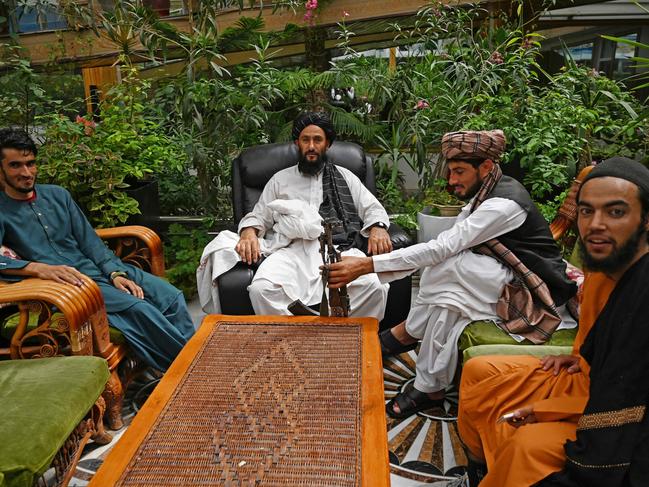 Taliban fighters sit in the mansion’s greenhouse yard. Picture: AFP