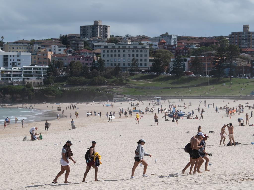 Beachgoers leave the sand after the closure of Bondi Beach. Picture: James Gourley