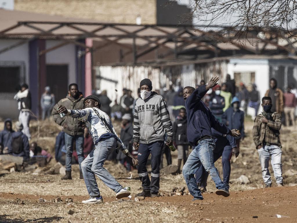 Disgruntled residents throw rocks as they confront police officers at the entrance of a partially looted mall in Vosloorus. Picture: AFP