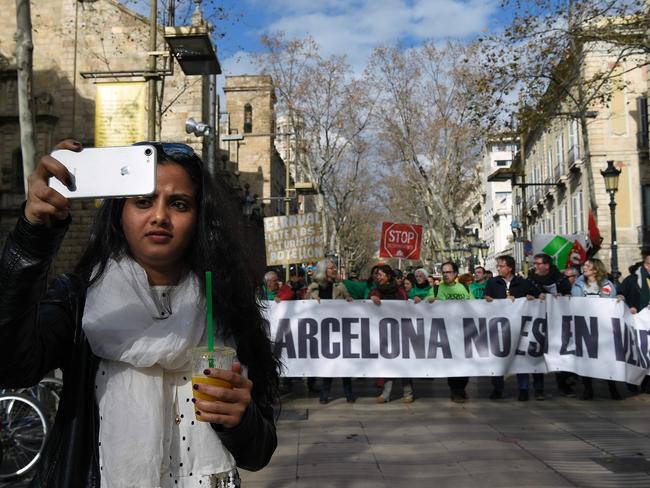 A tourist takes a selfie in front of a banner that says “Barcelona is not for sale” during a demonstration in Barcelona on January 28, 2017. Photo: AFP PHOTO/LLUIS GENE