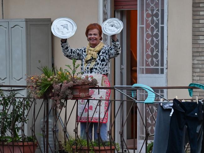 A resident of Rome clangs pot lids during a music flash mob aimed at livening up the city's silence during the coronavirus lockdown, March 13. Picture: Andreas Solaro/AFP