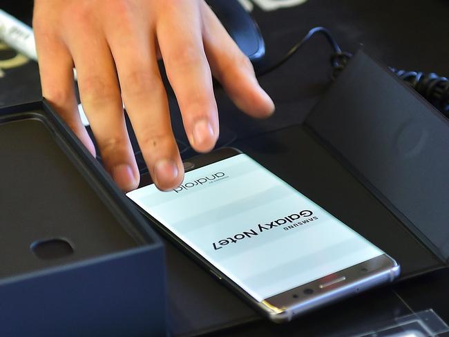 A South Korean employee provides a replacement Samsung Galaxy Note7 smartphone at a telecommunications shop in Seoul on September 19, 2016. Samsung started on September 19 to provide users of its Galaxy Note 7 smartphone the first batch of replacements with new batteries, after a series of battery explosions prompted a major recall worldwide. / AFP PHOTO / JUNG YEON-JE