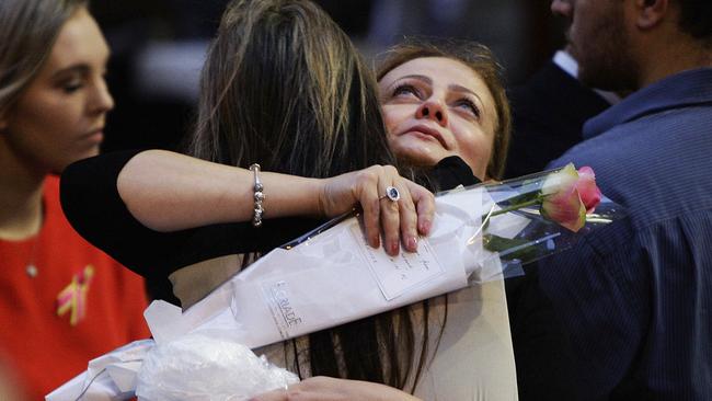 Lindt Cafe siege survivor Marcia Mikhael is embraced during a memorial service marking the first anniversary of Lindt Cafe Siege in Martin Place, Sydney, Australia, Dec. 15, 2015. An Iranian-born gunman took 17 people hostage at a central city cafe before police stormed the cafe in the early hours of Dec. 14, 2014. The gunman and two hostages were killed. (Lisa Maree Williams/Pool Photo via AP)