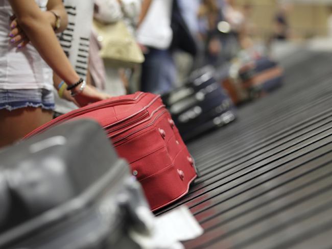 Suitcase on luggage conveyor belt in the baggage claim at airport