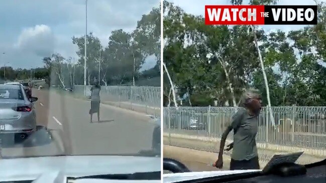 Woman stands in the middle of busy road